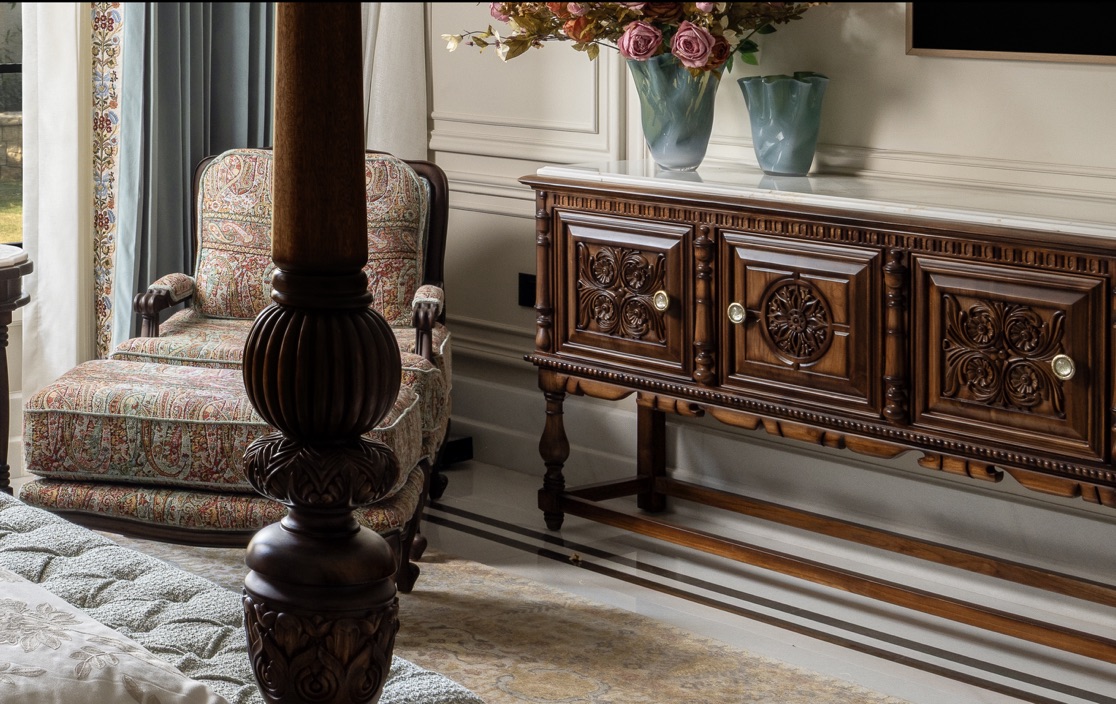 Carved dark wood bedpost beside a marble-topped sideboard