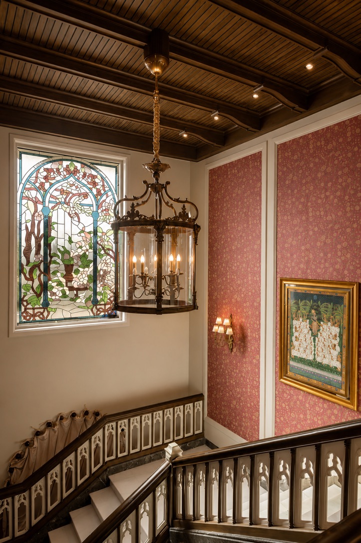 Stained glass window and brass lantern above a carved staircase
