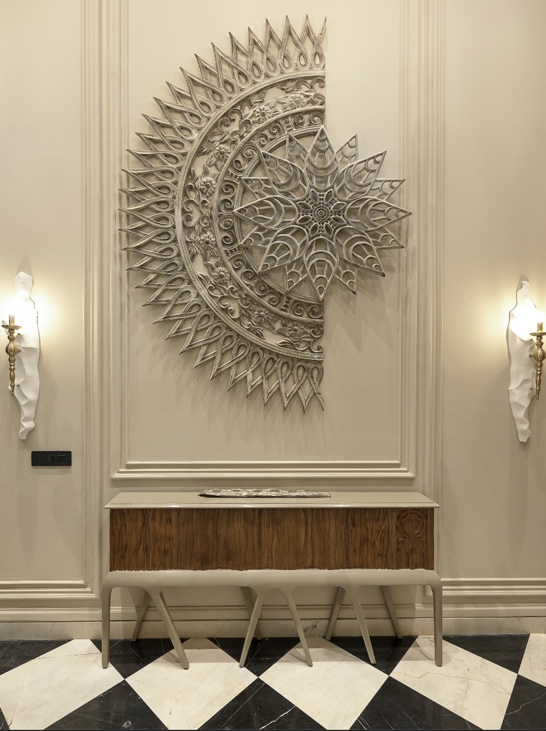 Silver sunburst wall sculpture above a console table