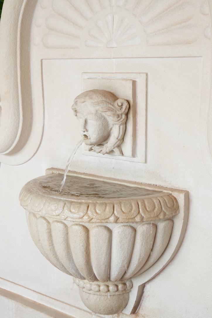 Carved limestone wall fountain with a mask spout