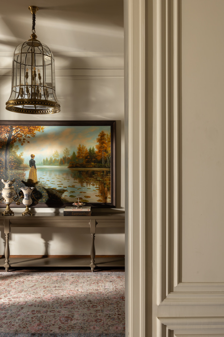 Framed lake landscape above a console table seen through a doorway