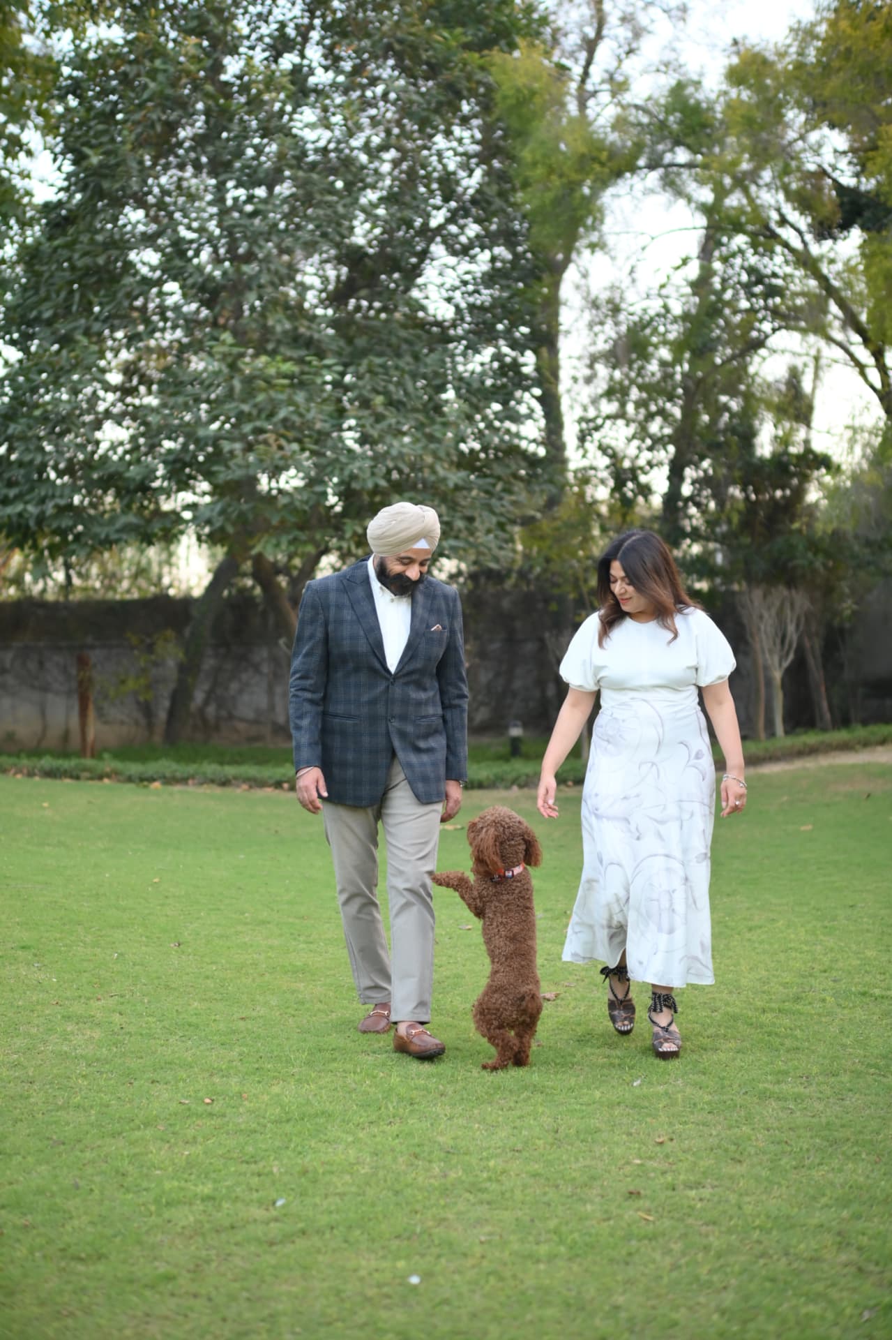 Mandeep and Dolly Sidana walking on a lawn with their dog