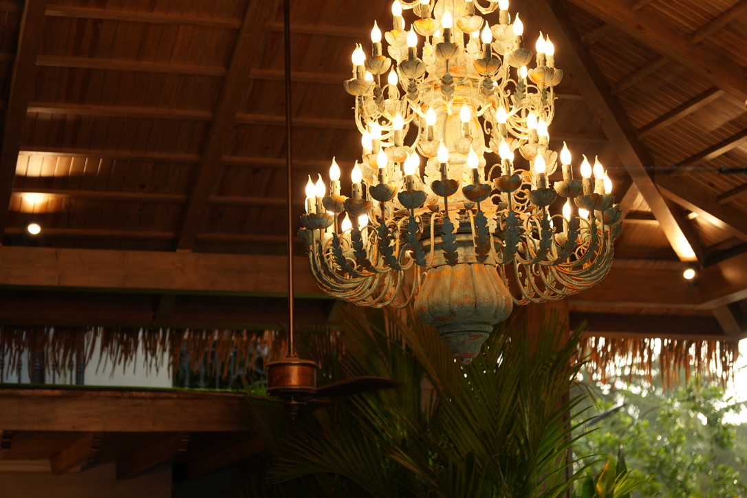 Tiered wrought iron chandelier beneath a thatched roof